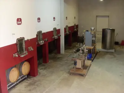 a row of wine barrels in a wine cellar at Chambres d'hôtes Domaine de Beaupré in Narbonne