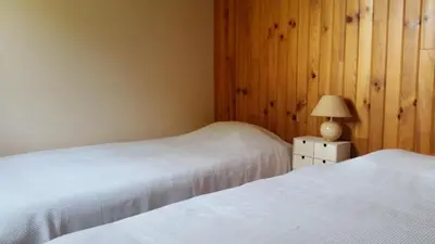a bedroom with two beds and a lamp on a night stand at Le Cers in Ribaute