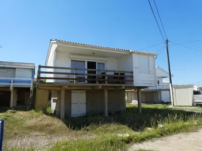 an old house with a porch with a balcony at UN CHALET EN BOIS A LA PLAGE in Gruissan