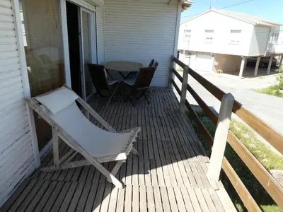 a rocking chair on a porch with a table at UN CHALET EN BOIS A LA PLAGE in Gruissan