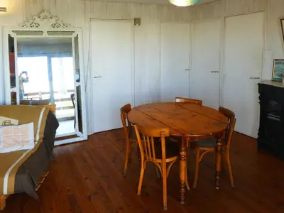 a room with a wooden table and chairs and a bed at UN CHALET EN BOIS A LA PLAGE in Gruissan