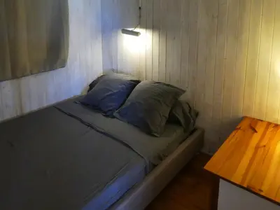 a bed with blue pillows in a room with a table at UN CHALET EN BOIS A LA PLAGE in Gruissan