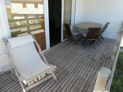 a rocking chair and a table on a porch at UN CHALET EN BOIS A LA PLAGE in Gruissan