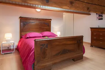 a bedroom with a large wooden bed with pink sheets at La Terrasse de Jules in Carcassonne