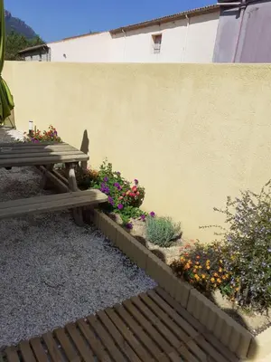 a wooden bench sitting next to a wall with flowers at Studio les trois chemins in Cucugnan