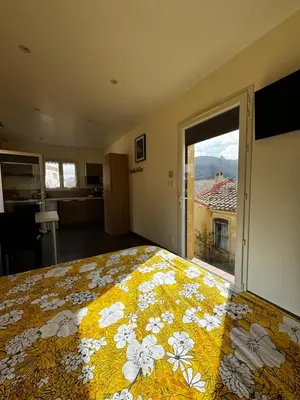 a bedroom with a bed and a large window at Studio les trois chemins in Cucugnan