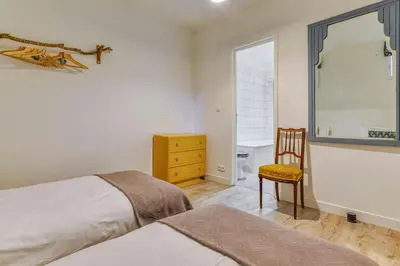 a bedroom with two beds and a chair and a window at La Calade in Montouliers