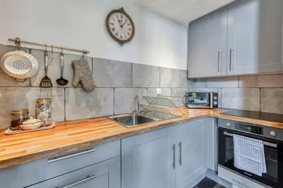 a kitchen with white cabinets and a clock on the wall at La Calade in Montouliers