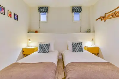 two beds in a small room with two lamps at La Calade in Montouliers