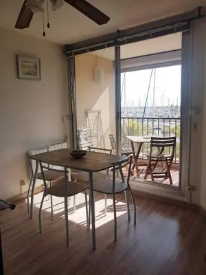 a dining room with a table and chairs and a balcony at T2 sur le port avec parking in Gruissan