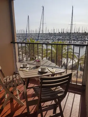 a table and chairs on a balcony with a view of a harbor at T2 sur le port avec parking in Gruissan