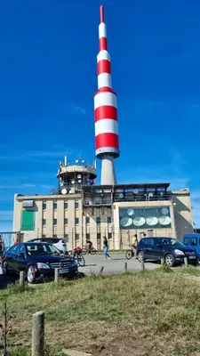 a lighthouse with cars parked in front of a building at chez Black and White in Les Martys