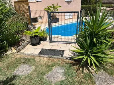 a gate in a yard with a pool and plants at Appartement Climatisé T3 Piscine et Parking in Pennautier
