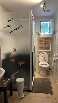 a bathroom with a toilet and some fish on the wall at Appartement Climatisé T3 Piscine et Parking in Pennautier