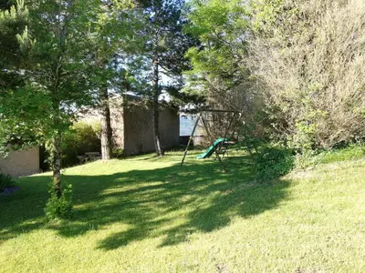 a yard with a swing set in the shade of trees at Domaine des Goudis in Bouisse