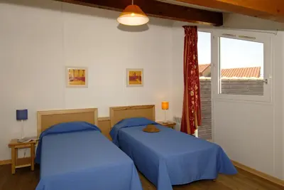 two beds in a room with a window at Goélia Le Village Club Marin in Port-la-Nouvelle