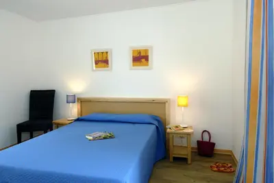 a bedroom with a blue bed and a chair at Goélia Le Village Club Marin in Port-la-Nouvelle