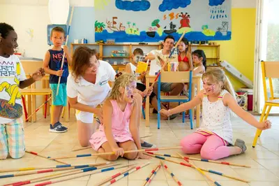a group of children sitting on the floor playing with colored sticks at Goélia Le Village Club Marin in Port-la-Nouvelle
