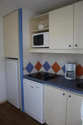 a kitchen with white cabinets and a microwave at Goélia Le Village Club Marin in Port-la-Nouvelle