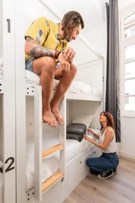 a man and a woman sitting on a bunk bed at Le Couvent - Hostel in Carcassonne