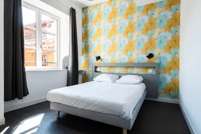 a bedroom with a bed with a blue and yellow wall at Le Couvent - Hostel in Carcassonne