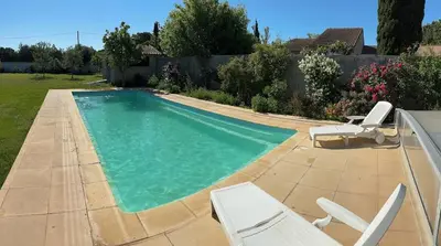 a swimming pool with two lawn chairs and a pair ofatoes at GITE Florence et Francis in Cuxac-dʼAude