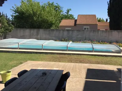 a picnic table in a backyard with a swimming pool at GITE Florence et Francis in Cuxac-dʼAude