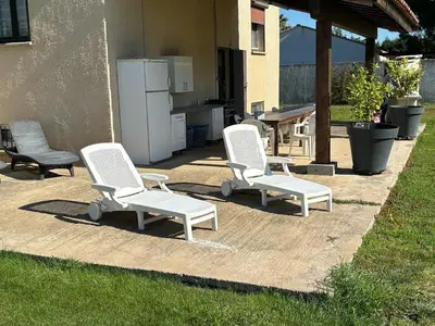 three white chairs sitting on a patio with a kitchen at GITE Florence et Francis in Cuxac-dʼAude