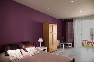 a bedroom with purple walls and a bed and a cabinet at Studio l'Obrador 25 m2 - Cuisine & terrasse - accès piscine in Rieux-Minervois