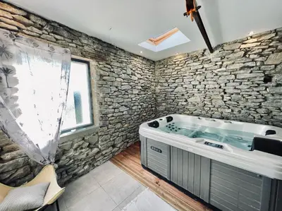 a stone walled bathroom with a tub and a window at Le cocon de Lenny in Conques-sur-Orbiel
