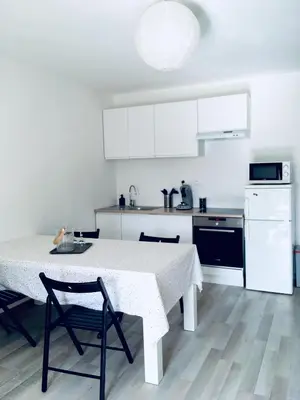 a white kitchen with a table and chairs and a stove at Le cocon de Lenny in Conques-sur-Orbiel