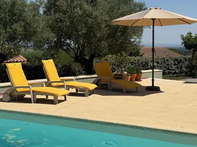 a group of chairs and an umbrella next to a pool at Villa in Caunes-Minervois with Private Pool in Caunes-Minervois