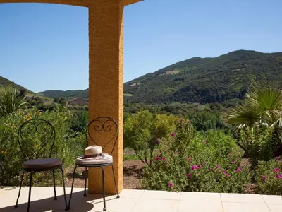 a table and two chairs on a porch with mountains at Roquebrun Villa with Pool in Roquebrun