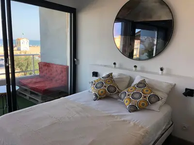 a bedroom with a bed with a mirror and a balcony at Appartement Vue Mer climatisé 2 chambres in Port-la-Nouvelle