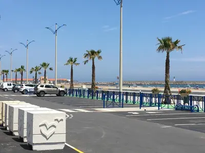 a parking lot at the beach with palm trees at Appartement Vue Mer climatisé 2 chambres in Port-la-Nouvelle