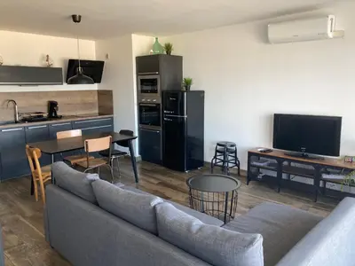 a living room with a couch and a kitchen at Appartement Vue Mer climatisé 2 chambres in Port-la-Nouvelle