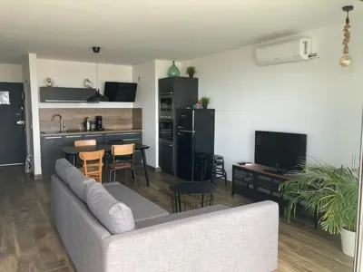 a living room with a couch and a kitchen at Appartement Vue Mer climatisé 2 chambres in Port-la-Nouvelle