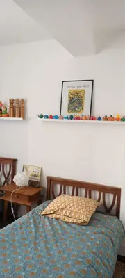 a bedroom with a bed and a shelf on the wall at Le Nid de Jeanne in Lézignan-Corbières
