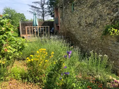a garden with flowers in front of a stone wall at Gîtes de Montcabirol in Mirepoix