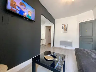 a living room with a couch and a tv on a wall at REPUBLIQUE Centre in Carcassonne