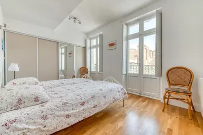a white bedroom with a bed and a chair at Wine Loft, Terrasse et Vue extraordinaire sur la cité médiévale in Carcassonne