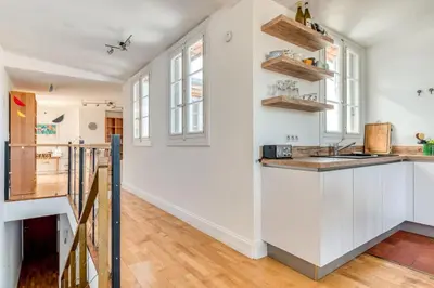 a kitchen with white walls and wooden floors at Wine Loft, Terrasse et Vue extraordinaire sur la cité médiévale in Carcassonne
