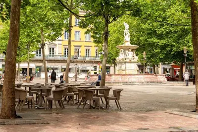 a group of tables and chairs in a park with a fountain at Wine Loft, Terrasse et Vue extraordinaire sur la cité médiévale in Carcassonne