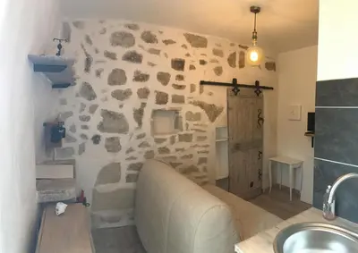 a bathroom with a stone wall with a couch in it at CHARMANT STUDIO in Capestang