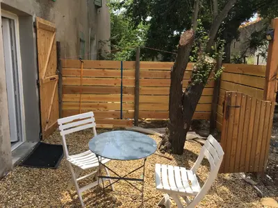 a table and two chairs and a tree in a yard at CHARMANT STUDIO in Capestang