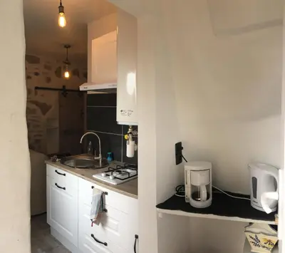 a white kitchen with a sink and a counter at CHARMANT STUDIO in Capestang