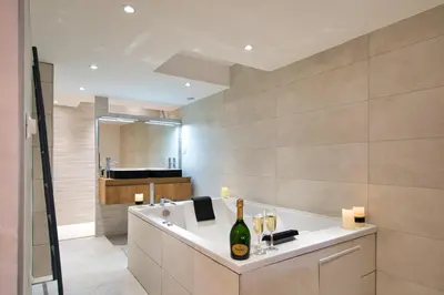 a bathroom with a bath tub with a bottle of wine at La suite numéro 1 in Carcassonne