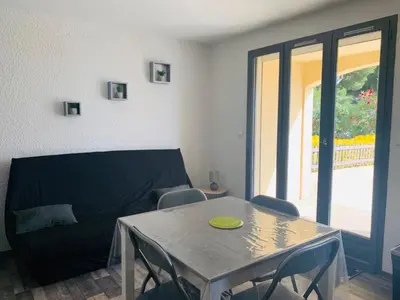 a living room with a table and chairs and a couch at La Pinède in Gruissan