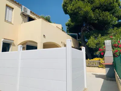 a white fence in front of a house at La Pinède in Gruissan
