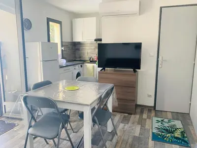 a kitchen with a table and chairs and a television at La Pinède in Gruissan